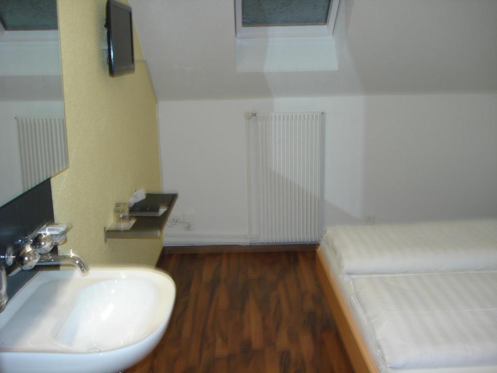 a bathroom with a white sink and a bed at Hotel Gregory in Zürich