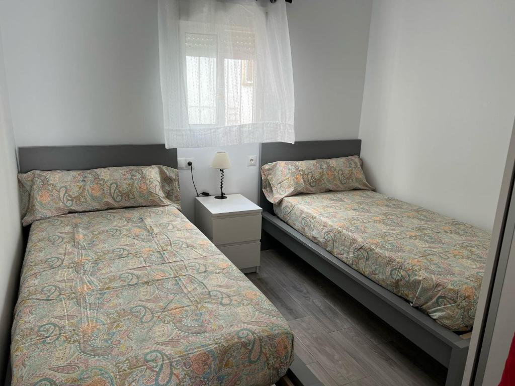 1 Schlafzimmer mit 2 Betten und einem Nachttisch in der Unterkunft Piso céntrico en Conil de la Frontera in Conil de la Frontera