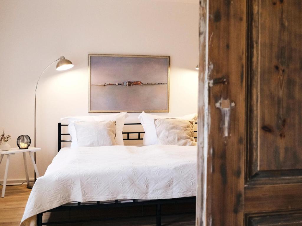 een slaapkamer met een bed met witte lakens en een schilderij bij Reethus Koppelkiek in Husby