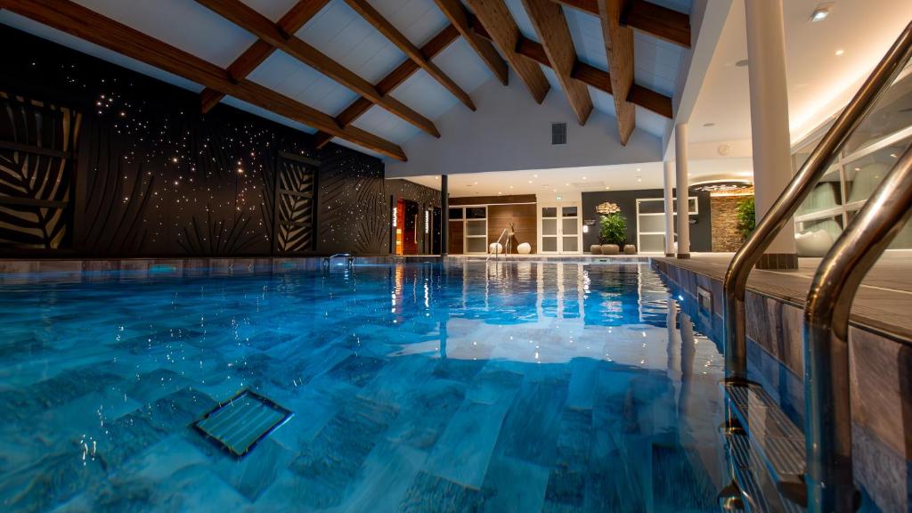 an indoor pool with blue water in a house at M&V Resort Camping in Langrune-sur-Mer
