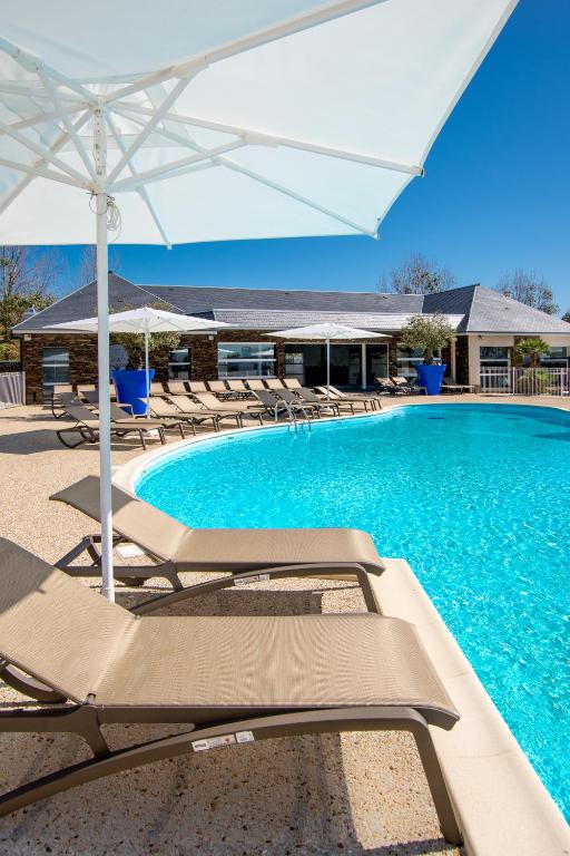 a swimming pool with lounge chairs and an umbrella at M&V Resort Camping in Langrune-sur-Mer
