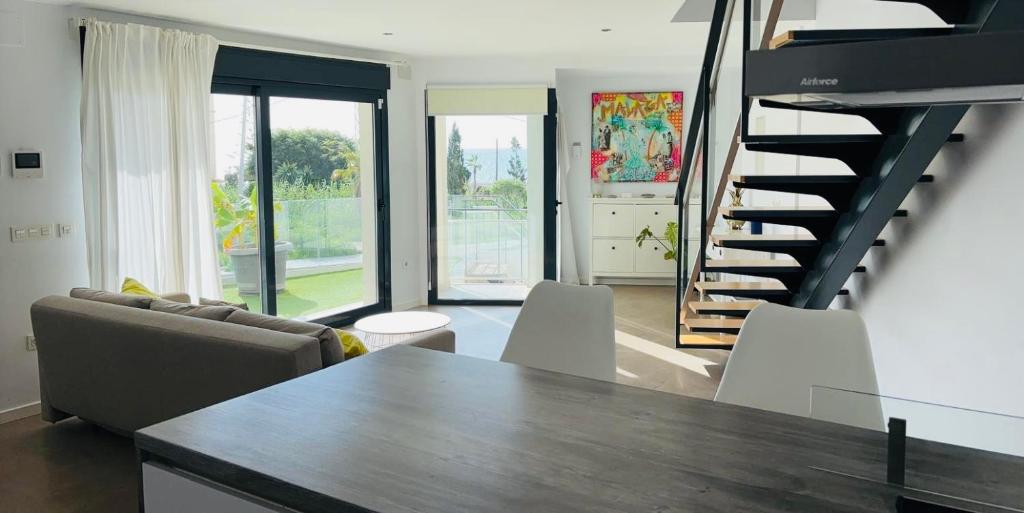 a living room with a table and a spiral staircase at Casa Paz en Benajarafe in Benajarafe