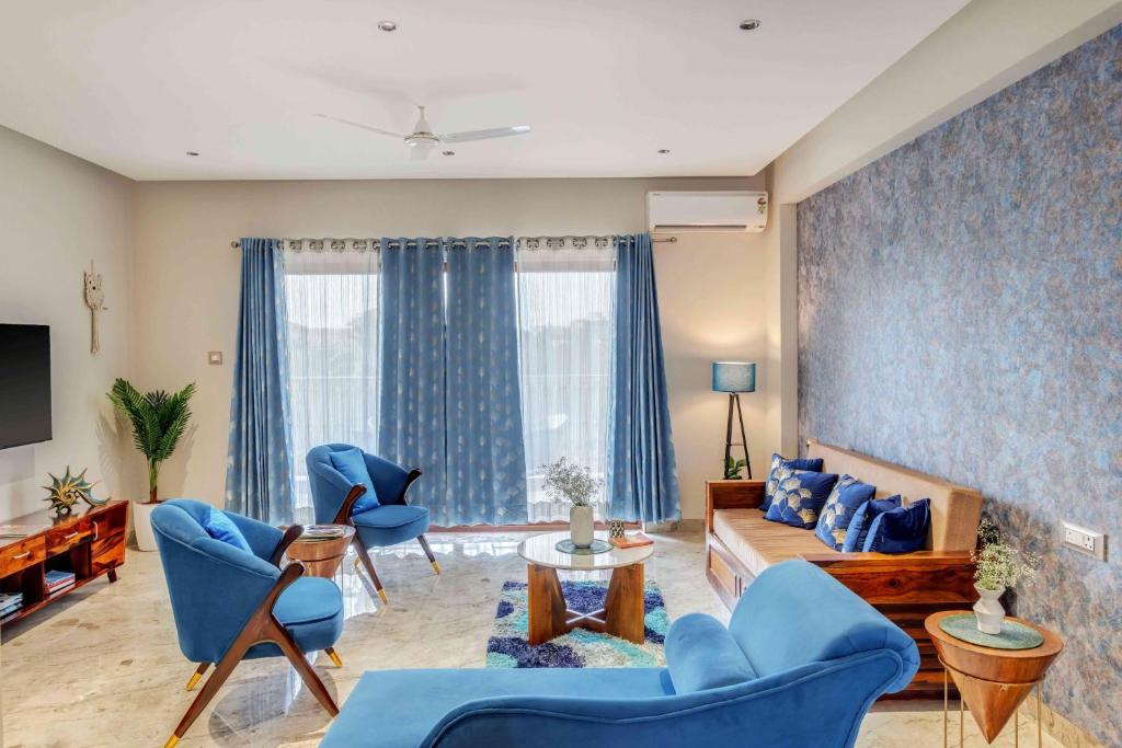a living room with blue chairs and a couch at Aqua 2 BHK Apartment by tisyastays in Candolim