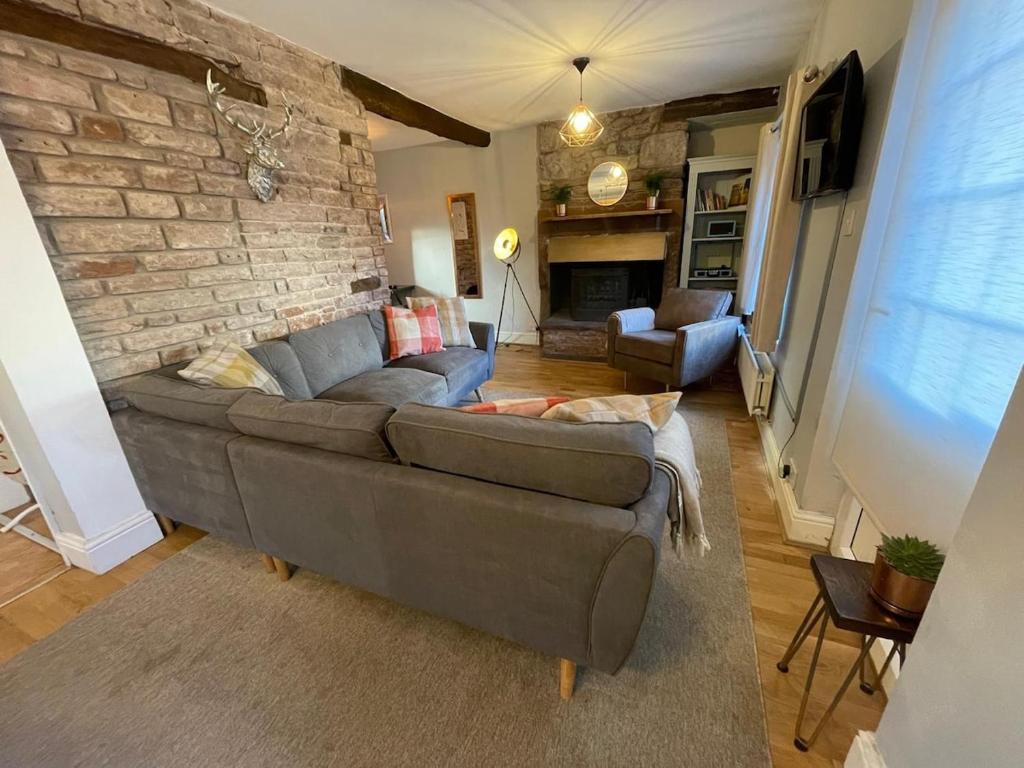 a living room with a couch and a brick wall at Charming 3 bedrooms Cottage in Tirril in Tirril