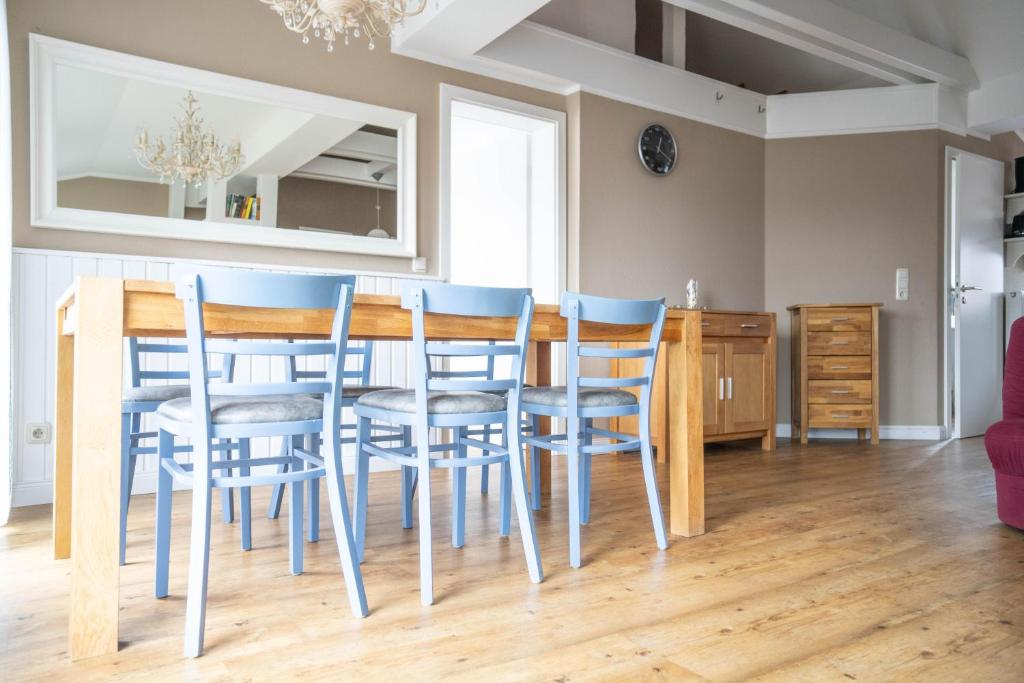a dining room with a table and blue chairs at Haus Alte Bäckerei Deichgraf in Born