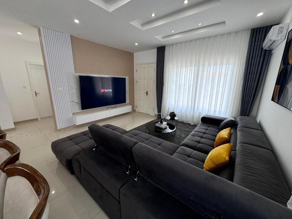 a living room with a black couch and a television at Luxury Escape Spacious Stay with Pool and Terrace in Luanda