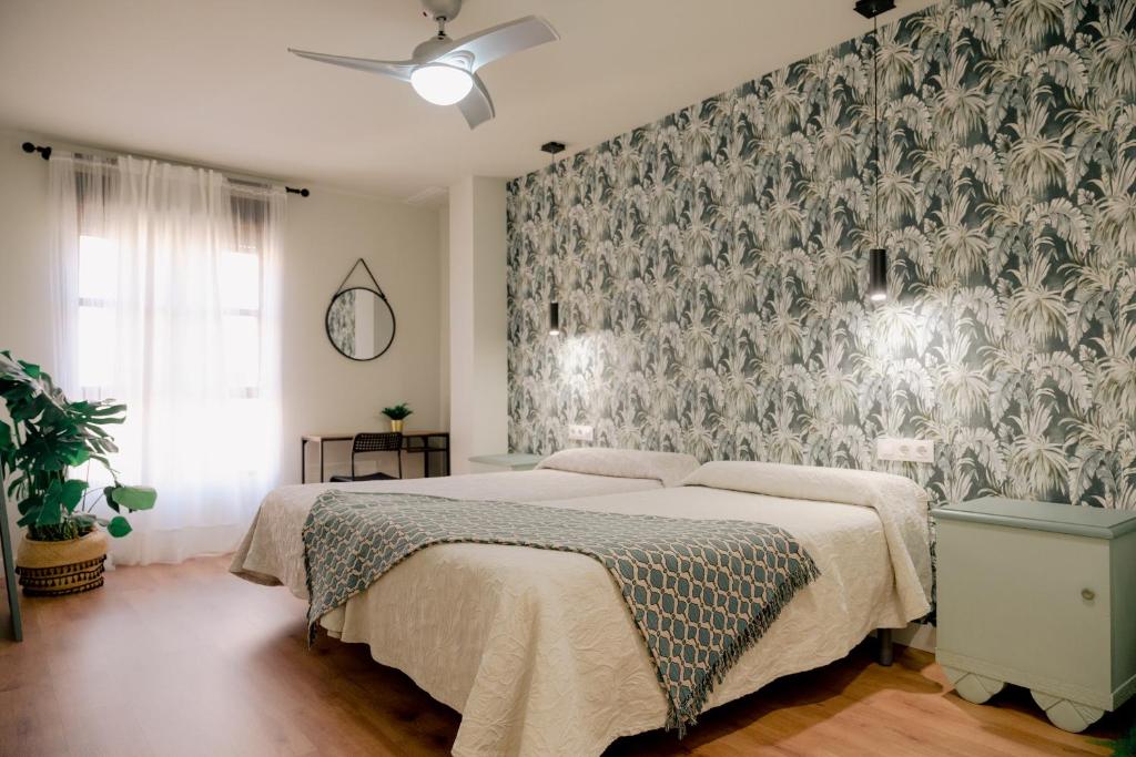アルカンタリージャにあるAcogedores apartamentos en el centroの花の壁紙を用いたベッドルーム1室(ベッド1台付)