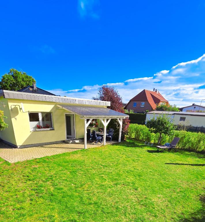 a small yellow house with a roof on a yard at Ferienhaus Ostsee-Oase Karlshagen in Ostseebad Karlshagen