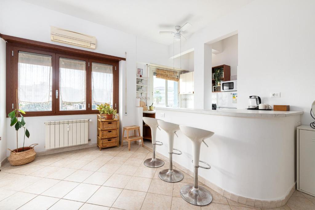 a white kitchen with a counter and stools at Tiny Boho Chic in Lido di Ostia