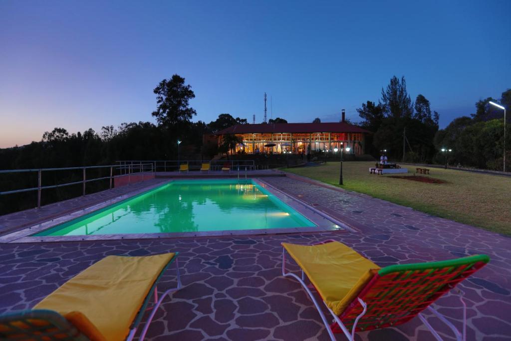 - une piscine avec 2 chaises et une maison dans l'établissement Goha Hotel, à Gonder
