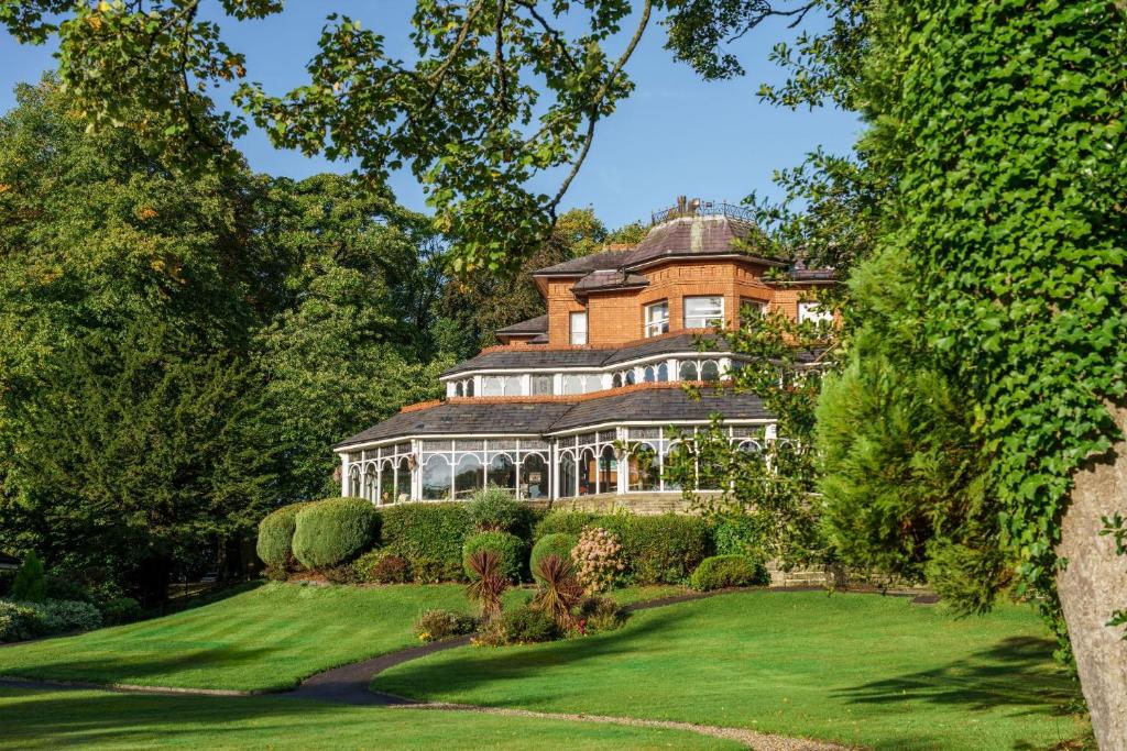 una casa grande en un césped verde con árboles en Macdonald Kilhey Court Hotel, en Wigan
