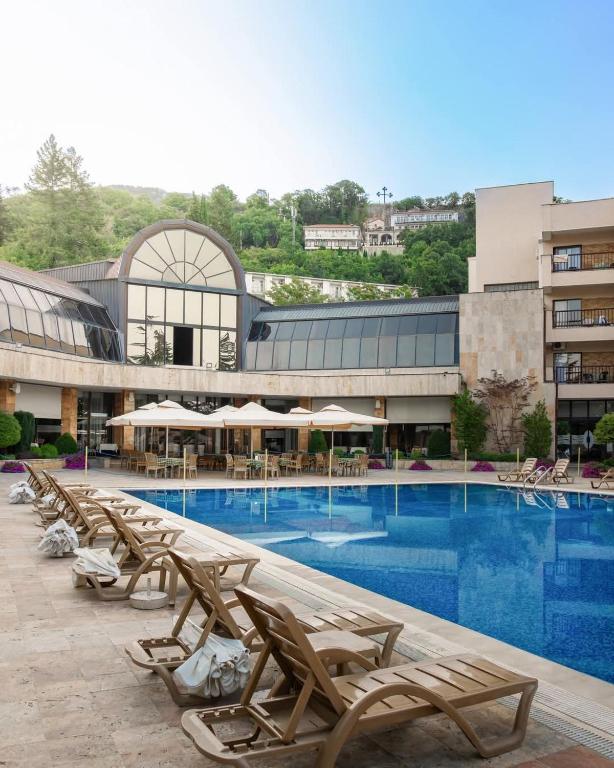 a pool with chaise lounge chairs in front of a building at Hotel Sileks in Ohrid