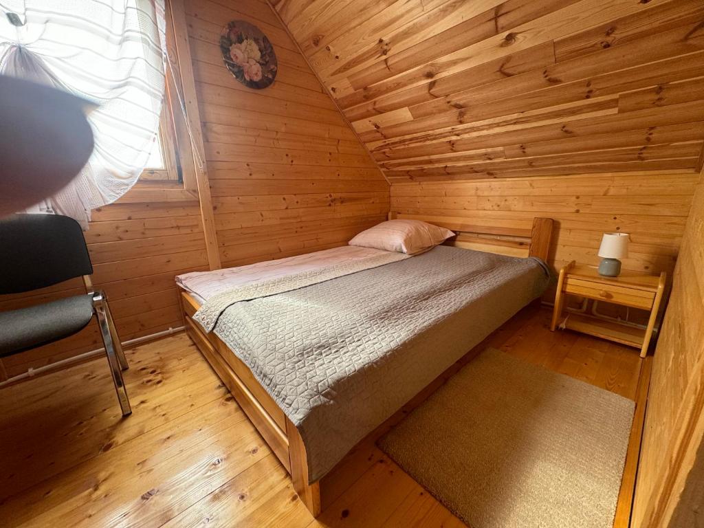 a small bedroom with a bed in a wooden cabin at Domki Letniskowe Martynka in Niechorze