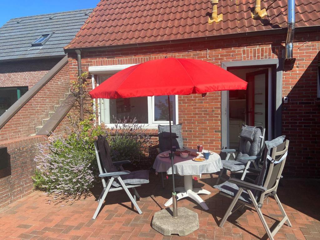a table and chairs under a red umbrella on a patio at Ruhe auf Borkum in Borkum