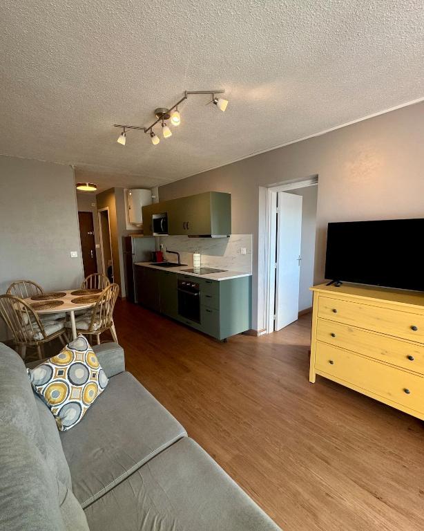 un salon avec un canapé et une télévision et une cuisine dans l'établissement Jolie appartement à Carnon Plage, à Mauguio