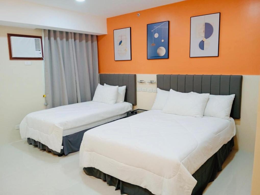 two beds in a hotel room with orange walls at Baba Staytion1 of SMDC Style Condo in Iloilo City