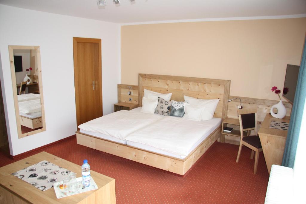 a bedroom with a bed and a table and a mirror at Landhaus Seehof in Füssen