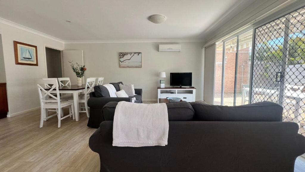 Una sala de estar con un sofá negro y una mesa. en Bougainvillea, en Sawtell