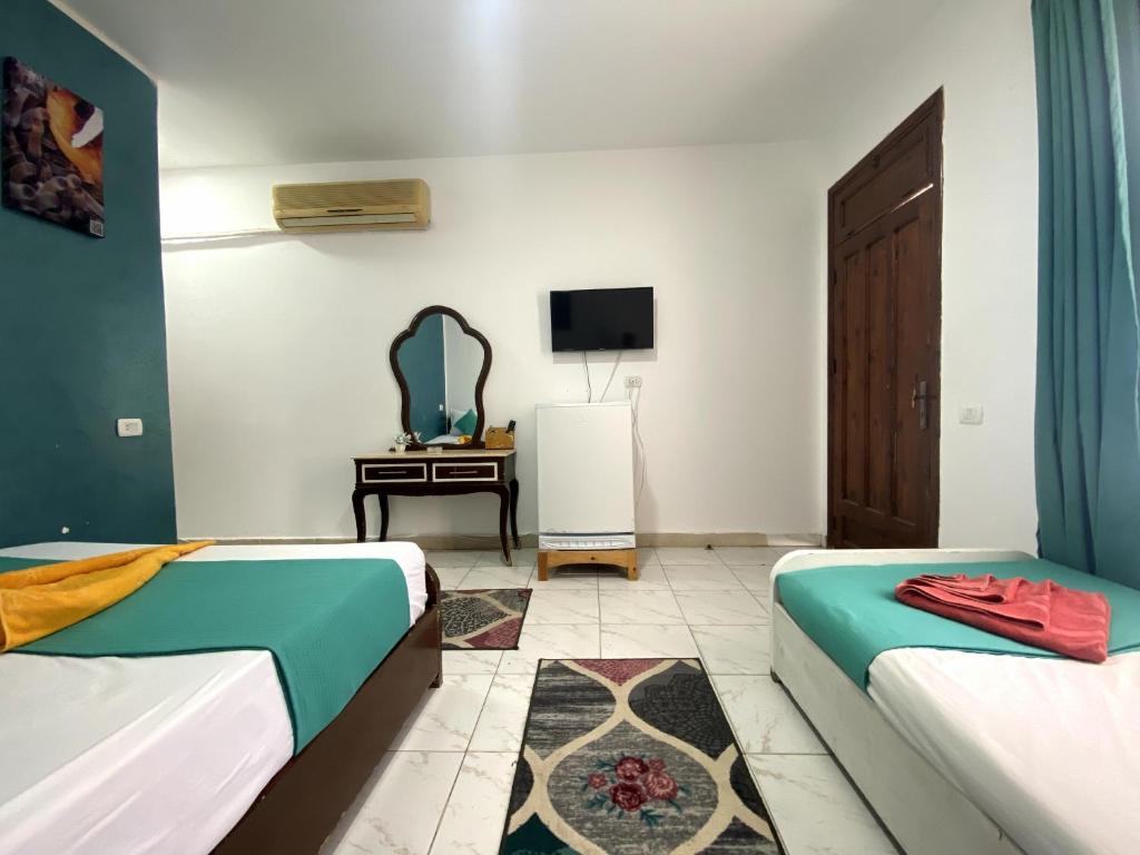 a room with two beds and a tv and a desk at Octopus Hotel in Dahab
