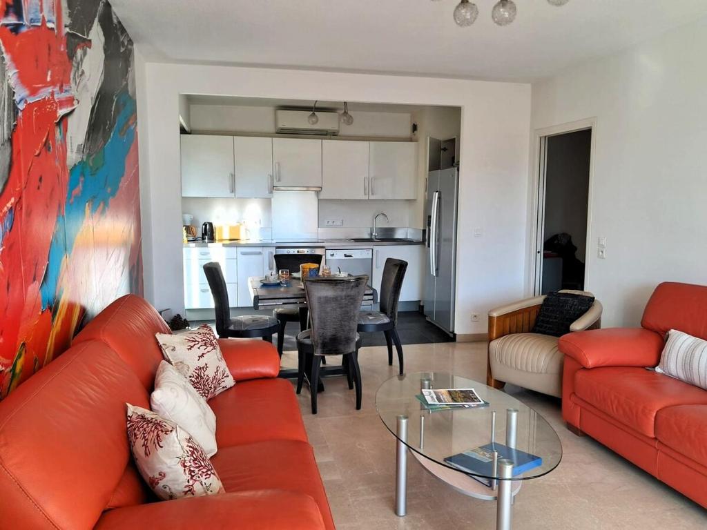 un salon avec un canapé rouge et une table dans l'établissement Le Beachcomber, à Antibes