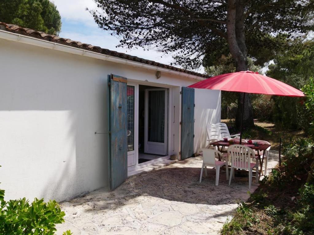 - une table et des chaises avec un parasol rouge sur la terrasse dans l'établissement ღ La Pause Retaise - Proche Plage, Jardin & Wifi, au Bois-Plage-en-Ré