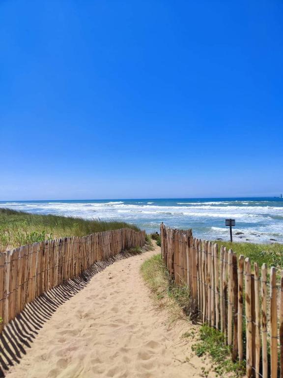une clôture en bois sur une plage avec l'océan dans l'établissement Maison 400m océan, à Brem-sur-Mer