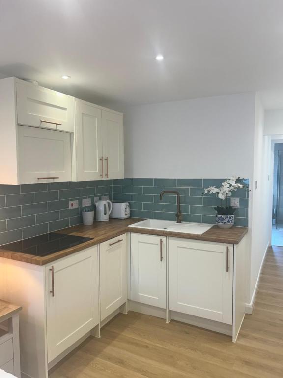 a kitchen with white cabinets and a sink at The Little Fern in Oxford