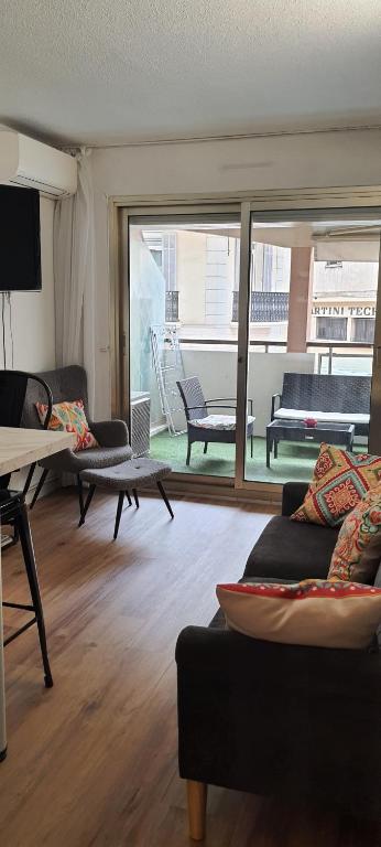 Elle comprend un salon doté de meubles et d'une grande fenêtre. dans l'établissement T2 Cannes center, à Cannes