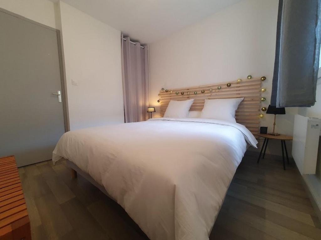 sypialnia z dużym białym łóżkiem z drewnianym zagłówkiem w obiekcie Dolce vita en centre ville w mieście Niort