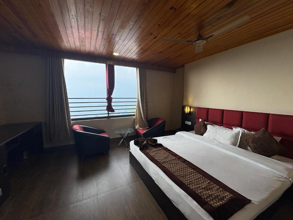 Un dormitorio con una cama grande y una ventana grande. en Hotel mmr manor&spa, en Gangtok