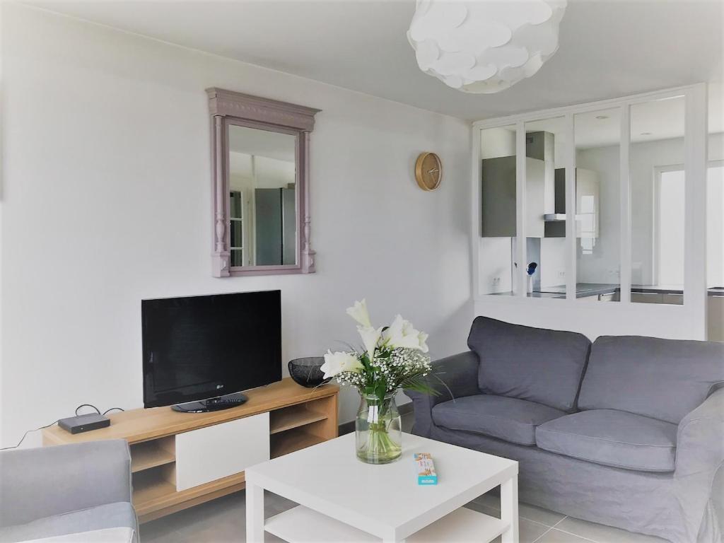 un salon avec un canapé et une télévision dans l'établissement Breizh Izel, vue mer et proche centre-ville, à Roscoff