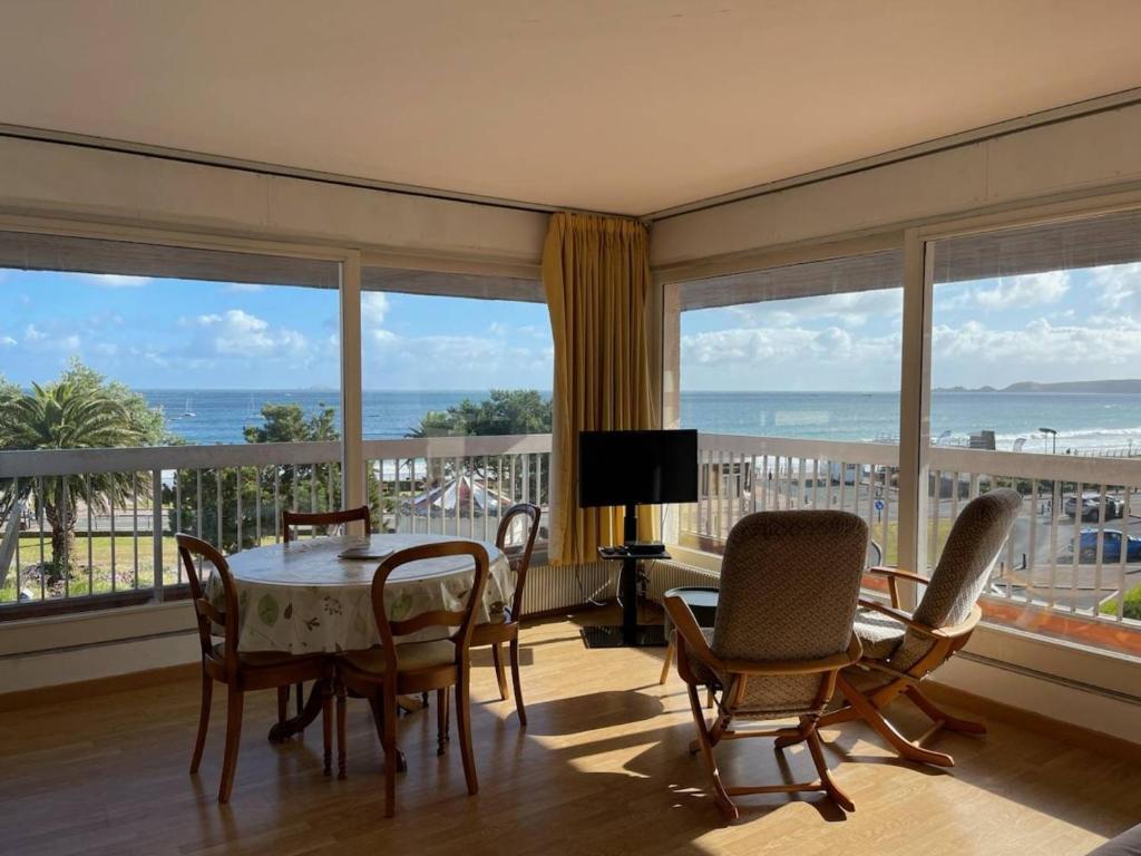 une salle à manger avec une table, des chaises et des fenêtres dans l'établissement Appartement avec terrasse, parking, plage de Trestraou à Perros-Guirec - FR-1-368-350, à Perros-Guirec