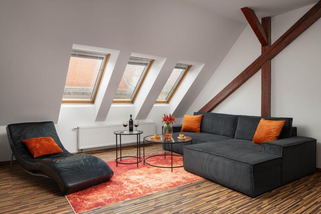 salon z czarną kanapą i 2 krzesłami w obiekcie Old Town Apartment Spilberk by Goodnite cz w mieście Brno