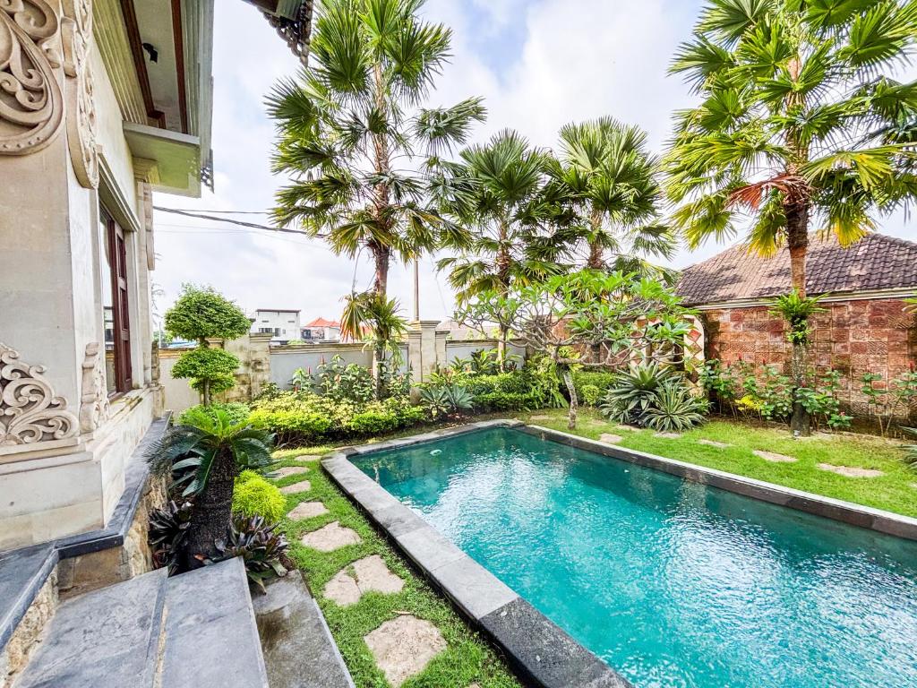 a swimming pool in front of a house with palm trees at Swikara White House in Sukawati