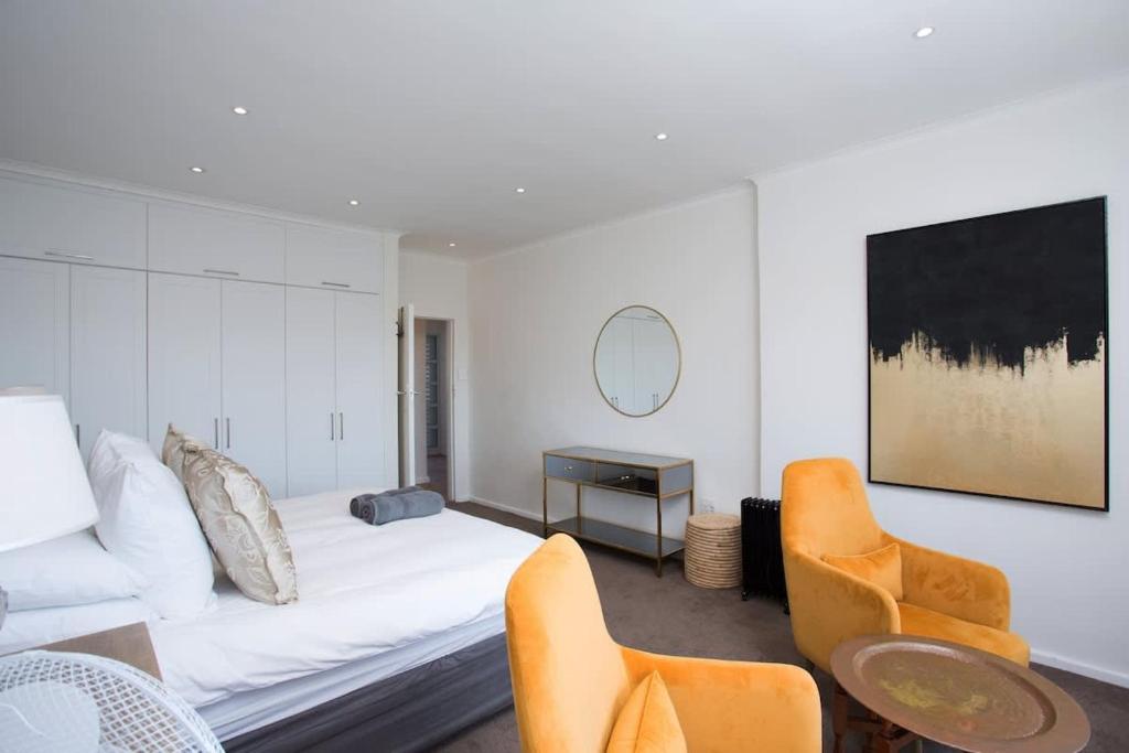 een woonkamer met een bank, een tafel en stoelen bij Comfort & Style apartment 200m to beach with parking in Kaapstad