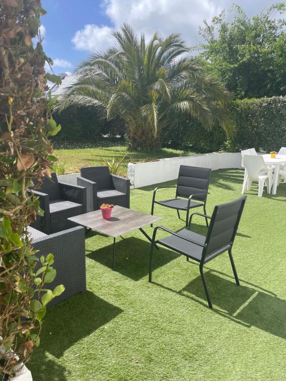 d'une terrasse avec des chaises et une table sur la pelouse. dans l'établissement Location 6-8 personnes avec jardin 15 mn à pied du port, au Palais