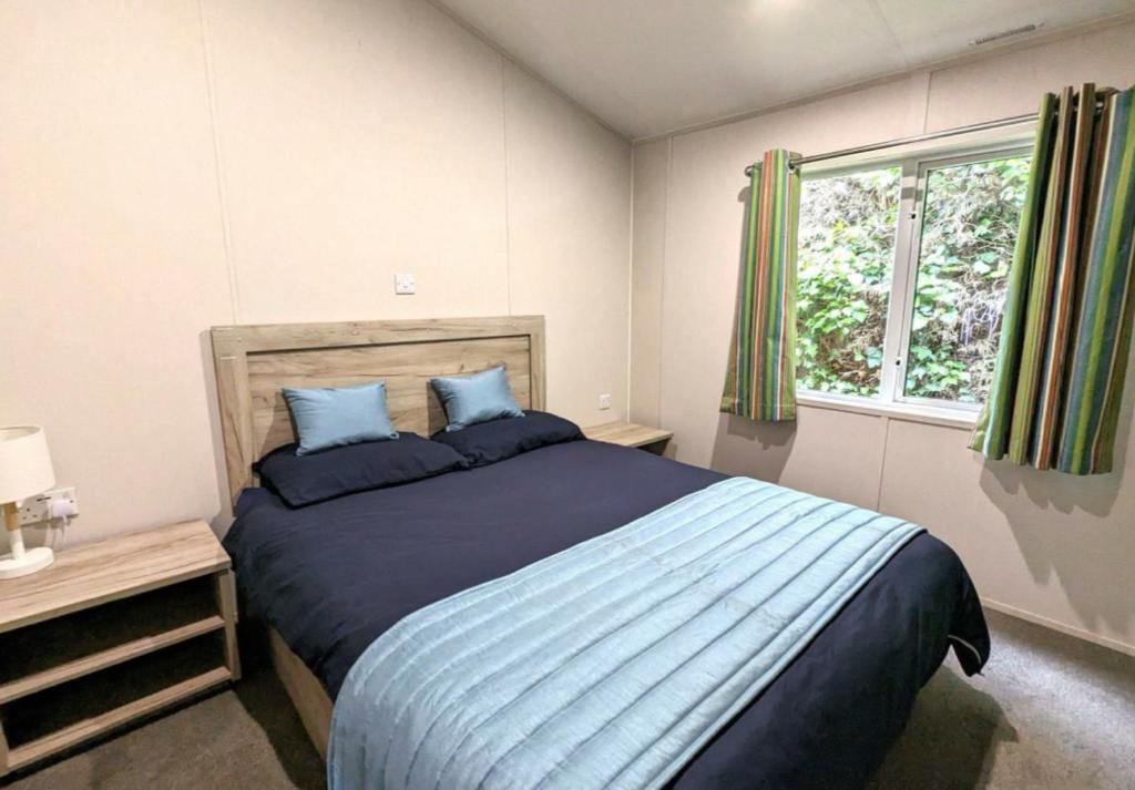 a bedroom with a bed with blue pillows and a window at Yellow Bush Lodge in Haven Street