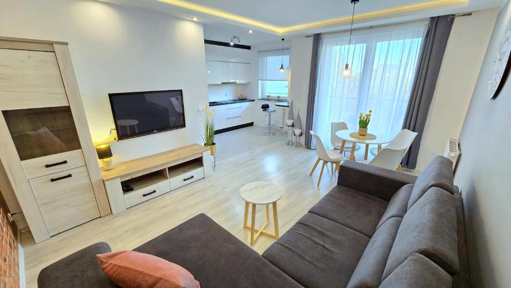 a living room with a couch and a tv and a table at RIVERS Apartment in Kołobrzeg