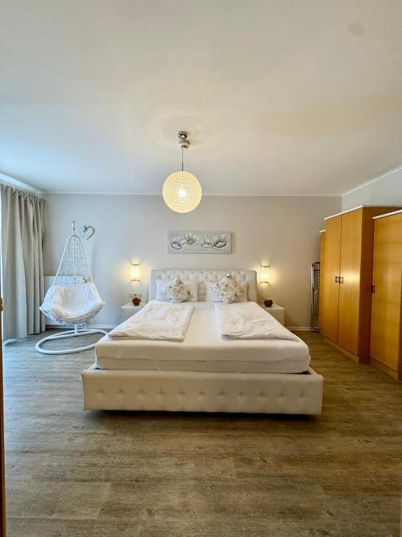 a bedroom with a large white bed and a chair at HappyStayApartments in Villach