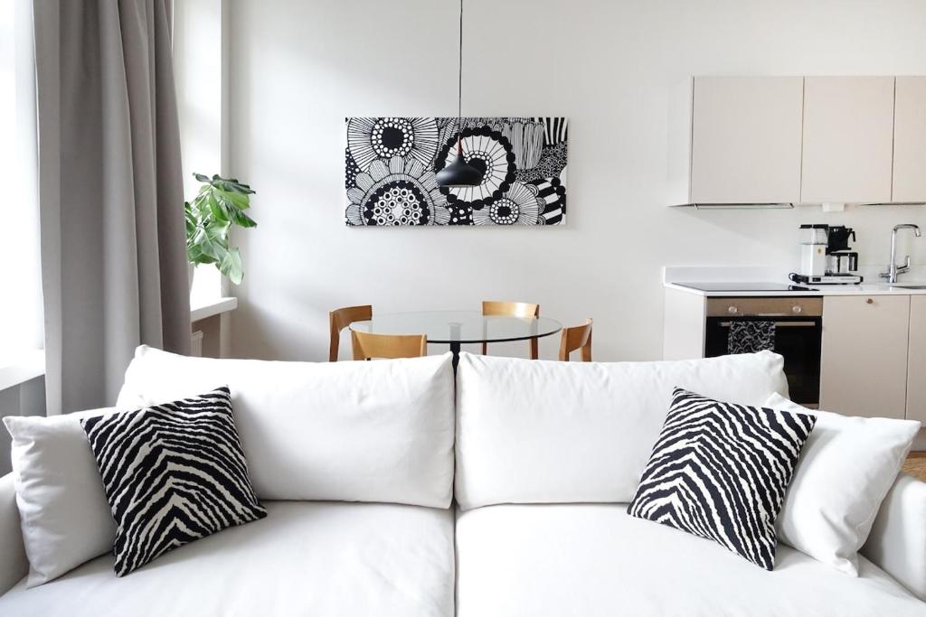 a white couch with black and white pillows in a kitchen at Stylish Design Studio Next to The Parliament House in Helsinki