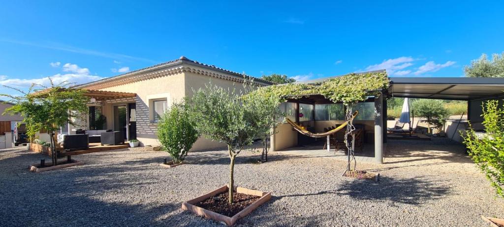 une maison avec un arbre dans une cour dans l'établissement Gîte Bevennes maison individuelle au calme, à Ruoms