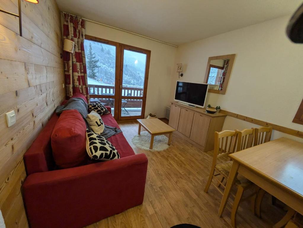 ein Wohnzimmer mit einem roten Sofa und einem Tisch in der Unterkunft Lumière des Neiges - 6 pers - 2 SDB - 1 terrasse - Pieds des pistes in Valmeinier