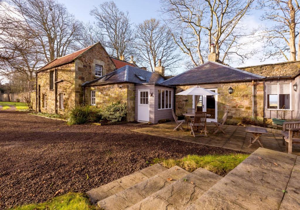 une maison en pierre avec une table et un patio dans l'établissement Luffness Castle Cottage, à Aberlady