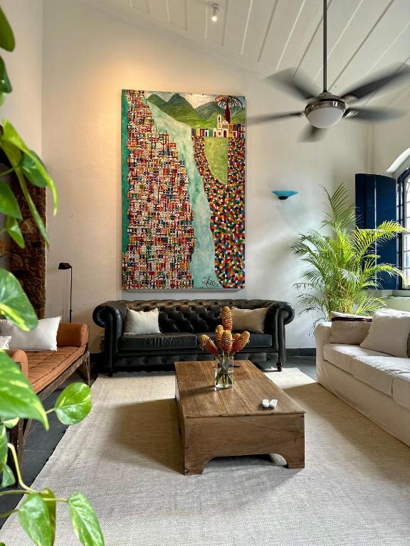 a living room with a couch and a painting on the wall at Casa Odara Paraty in Paraty
