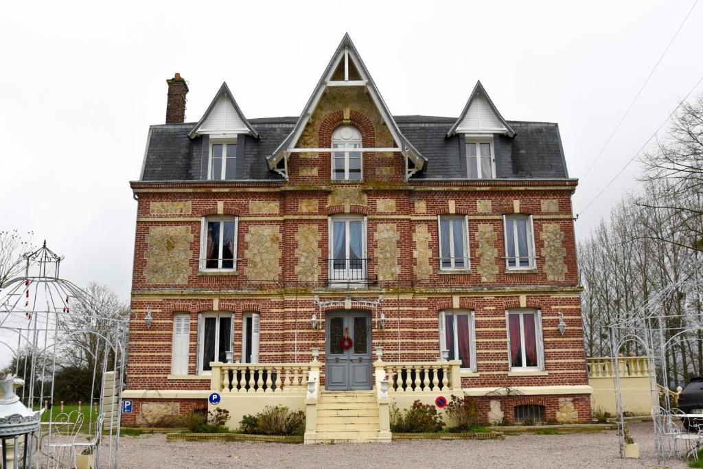 une grande maison en briques rouges avec un toit dans l'établissement Le Manoir de La Baronnie, à Norrey-en-Auge