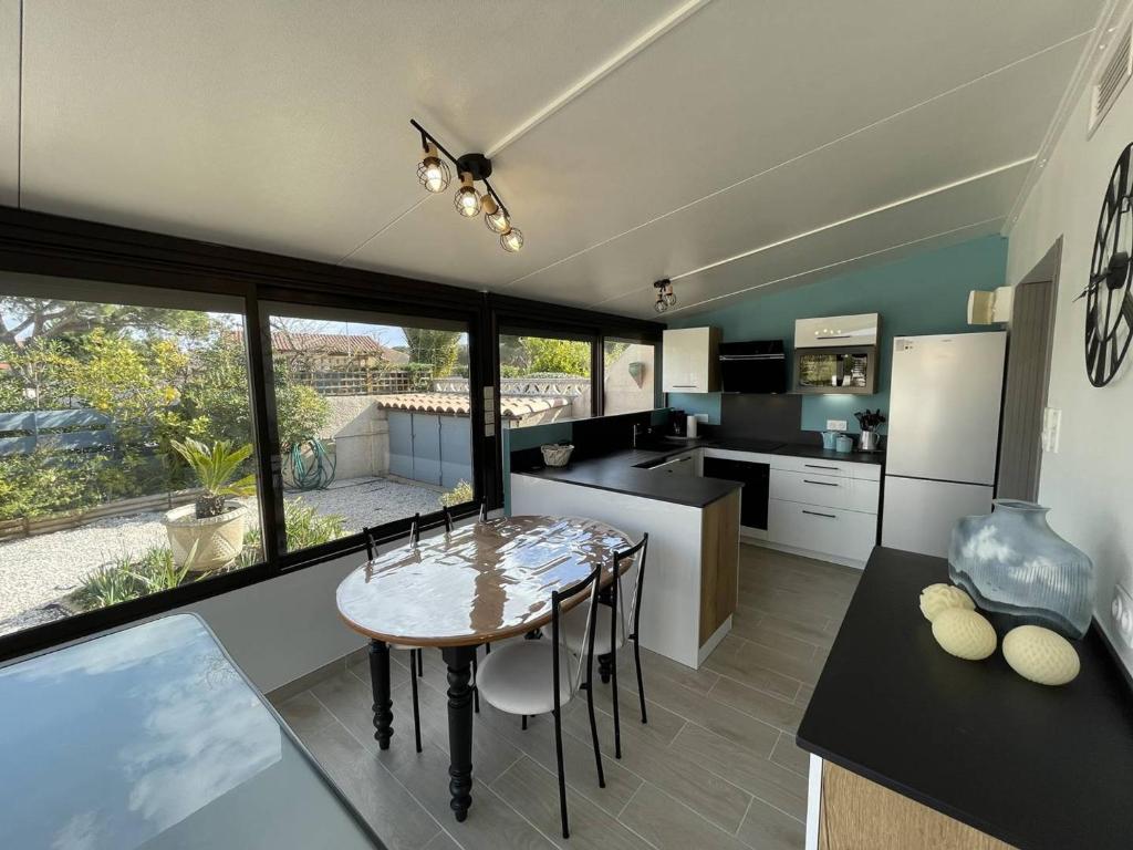 une cuisine avec une table et une grande fenêtre dans l'établissement Charmante Villa T3 Climatisée avec Véranda, Terrasse et Jardinet - Proche Plage et Commerces - FR-1-106-54, à Saint-Cyprien
