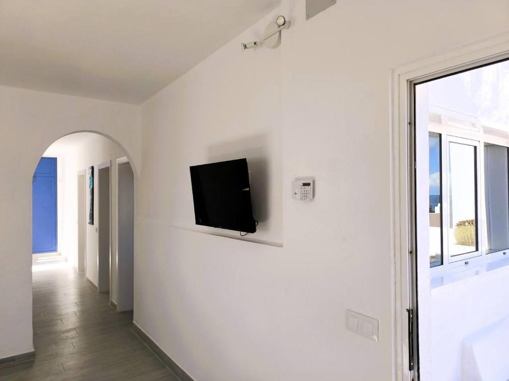 a living room with a tv on a white wall at Casa Lila, paz junto al mar in Guatiza