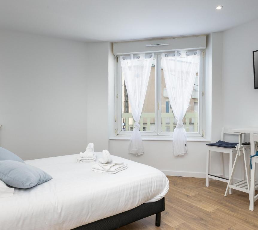 une chambre blanche avec un lit et deux fenêtres dans l'établissement Notre Dame de Rumengol, à Brest