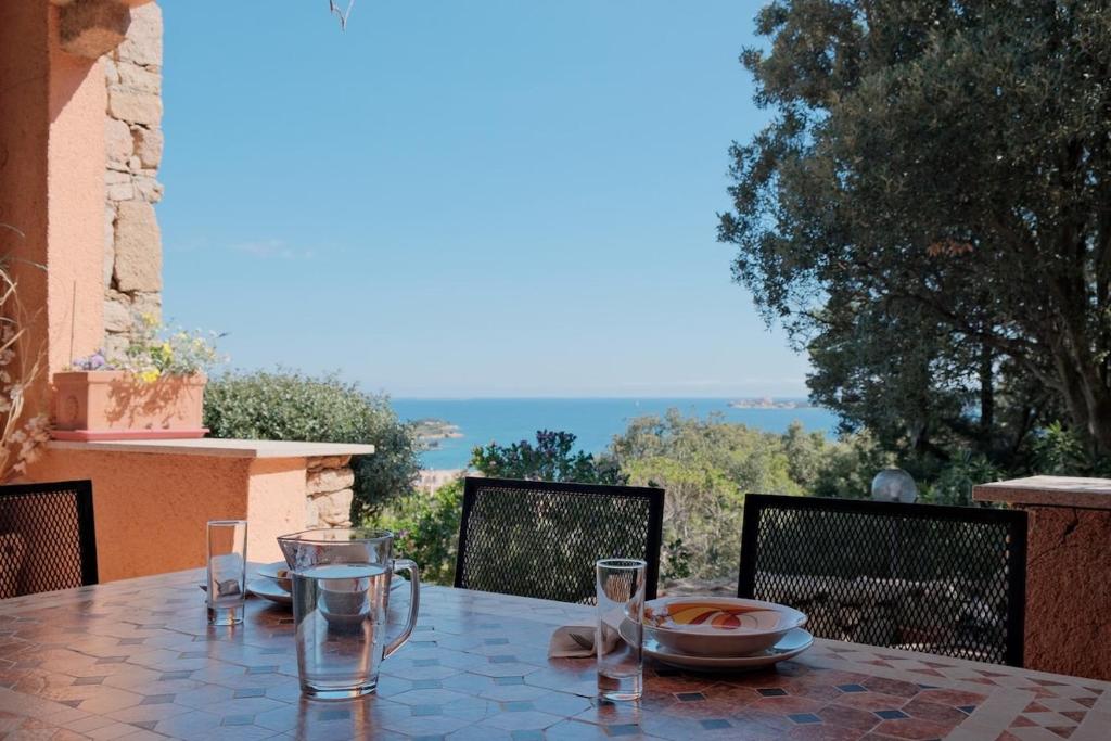 a table with a plate of food and glasses on a balcony at Vista Mare mozzafiato, a un minuto dalla spiaggia! in Cannigione