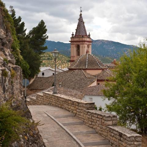 a building with a clock tower and a stone wall at Al Lago in Zahara de la Sierra